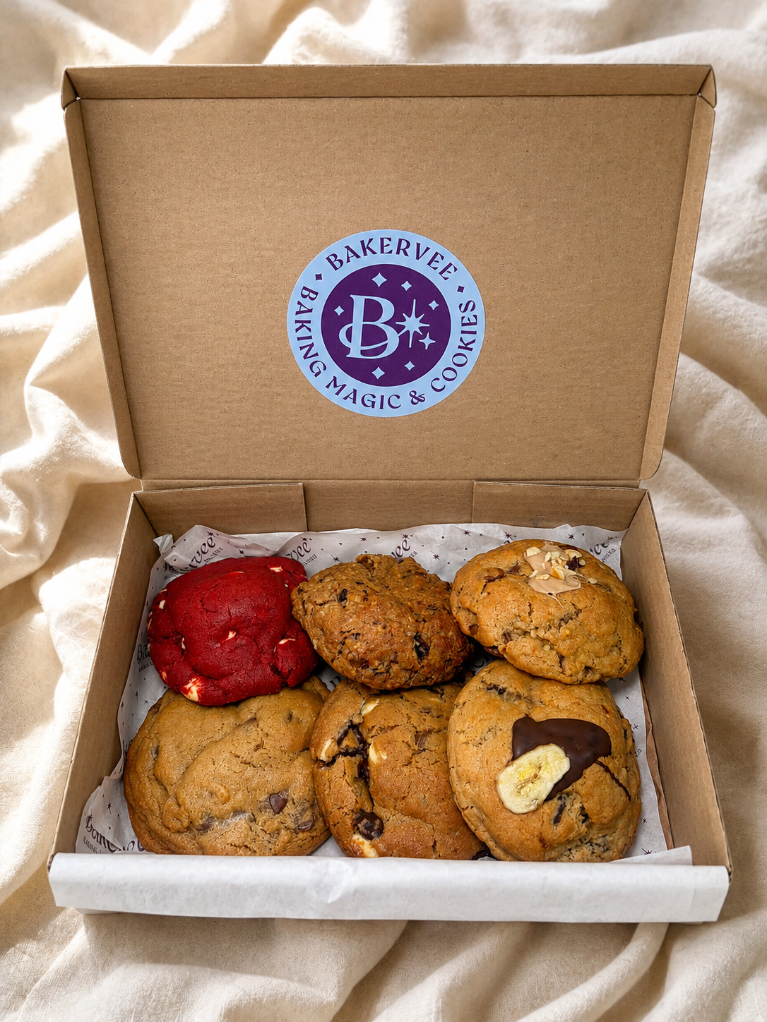 An open Bakervee gift box of six freshly baked premium cookies on branded tissue paper